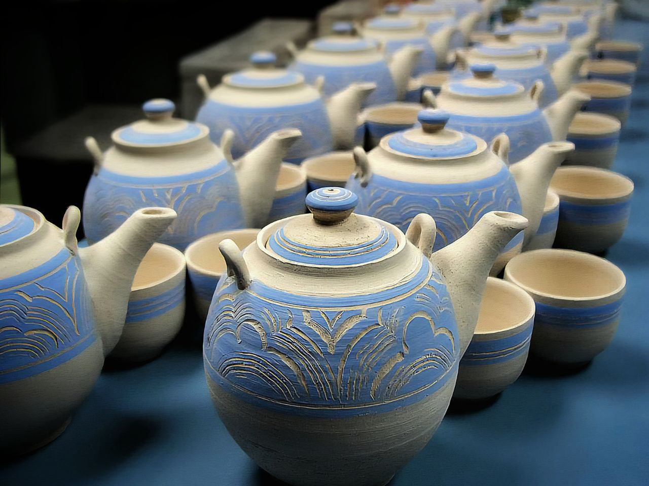 Row of handcrafted blue-and-white teapots created through a ceramic commission project at Urth & Phire Ceramic Studio
