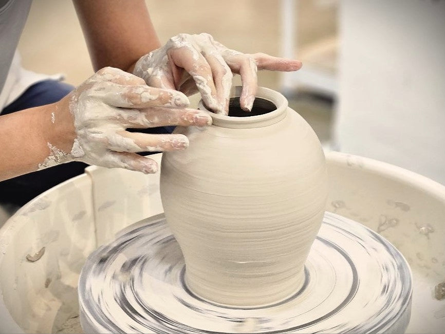 Close-up of a student shaping a clay pot on a pottery wheel during a hands-on class at Urth & Phire Ceramic Studio, Singapore