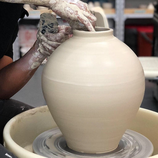 Ceramic artist throwing tall vessel moon jar on pottery wheel at Urth & Phire Ceramic Studio